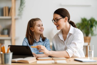 Okula dönelim. Mutlu çocuk ve yetişkin masada oturuyor. Ödev yapan ya da online eğitim alan kız.