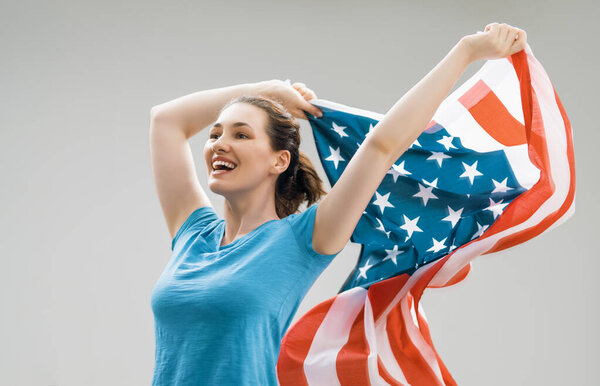 Patriotic holiday. Happy young woman with American flag. USA celebrate 4th of July.