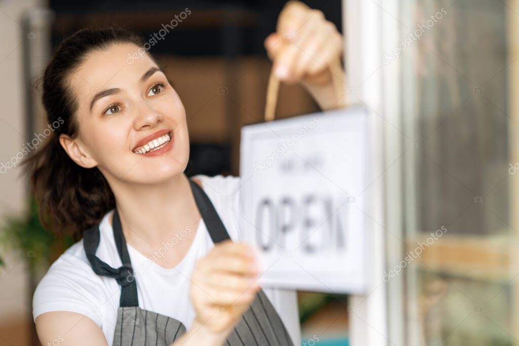 Small business owner smiling and holding the sign for the reopening of the place after the quarantine due to covid-19.