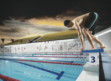Swimmer jumping from starting block in a swimming pool clipart