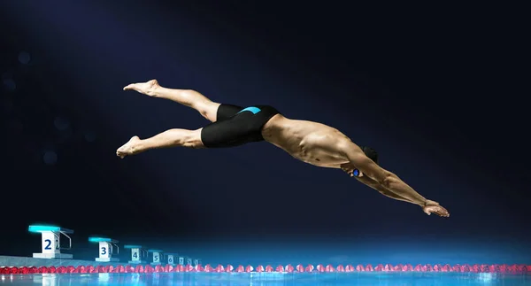 Пловец прыгает из стартового блока в бассейне — стоковое фото