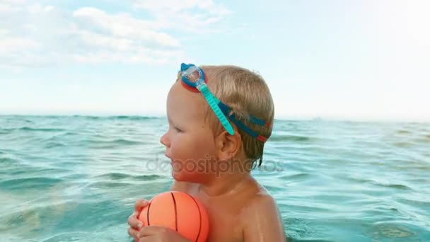 Niño feliz juega con la pelota en el mar cámara lenta . — Vídeos de Stock