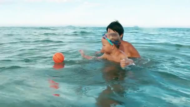 Мальчик и мать играют с мячом в море замедленной съемки — стоковое видео