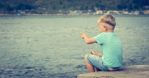 Χαριτωμένο αγόρι Καυκάσιος επισημαίνοντας με φοντο τη θαλασσα — Φωτογραφία Αρχείου