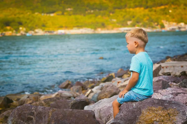 Lindo chico caucásico sentado en la playa —  Fotos de Stock