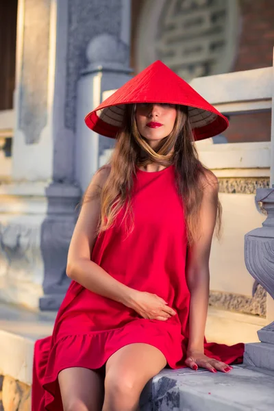 一个戴着红色锥形帽的漂亮女人在户外的时装肖像 — 图库照片