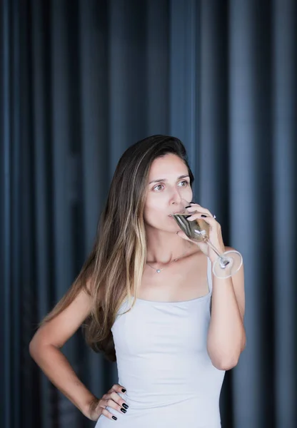 一个喝白葡萄酒的漂亮女人的室内画像 — 图库照片