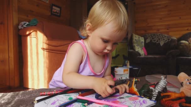 Милая маленькая девочка рисует цветными карандашами — стоковое видео