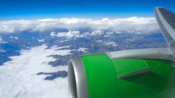 Hermosa vista a través de la ventana del avión, avión volando por encima de las nubes y las montañas — Vídeo de stock