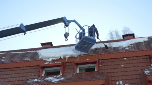 Рабочий убирает снег на крыше здания — стоковое видео