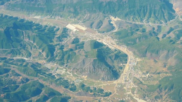 Hermosa vista a través de la ventana del avión, avión volando por encima de la ciudad en las montañas — Vídeos de Stock