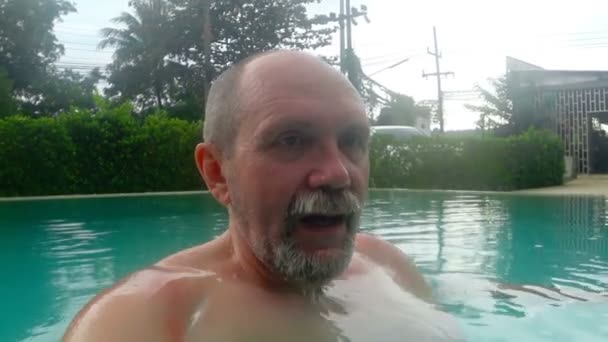 A man dives under the water in the pool and lets bubbles — Stock Video