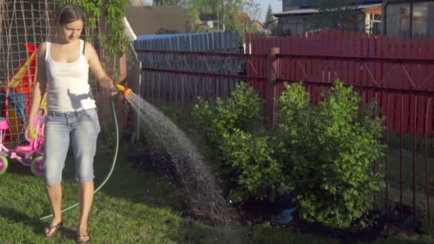 Женщина поливает газон — стоковое видео