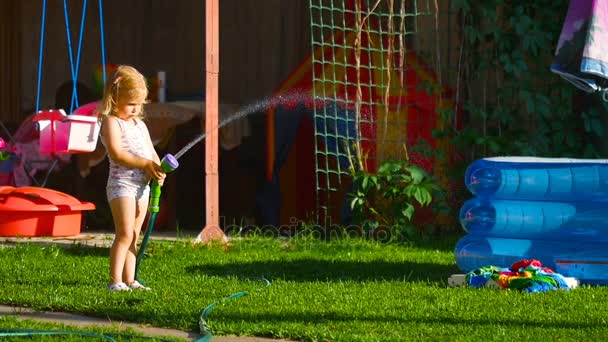 Liten flicka vattna gräsmattan — Stockvideo