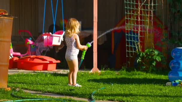 kleines Mädchen wässert Rasen