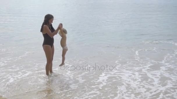 Mutter mit zweijähriger Tochter läuft am Sandstrand entlang — Stockvideo