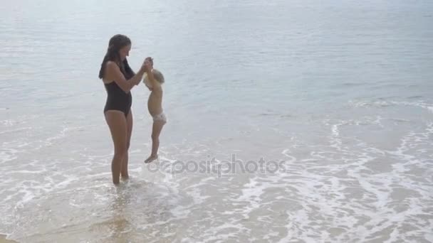 Mãe com uma filha de dois anos andando ao longo da praia — Vídeo de Stock