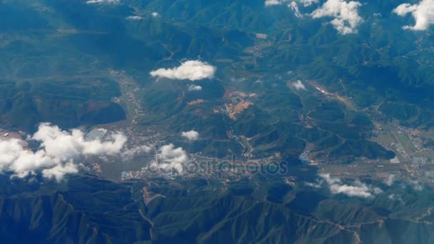 Beautiful view through airplane window, airplane flying above city in mountains — Stock Video