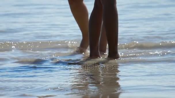 Pies masculinos y femeninos están de pie en la playa de arena — Vídeos de Stock