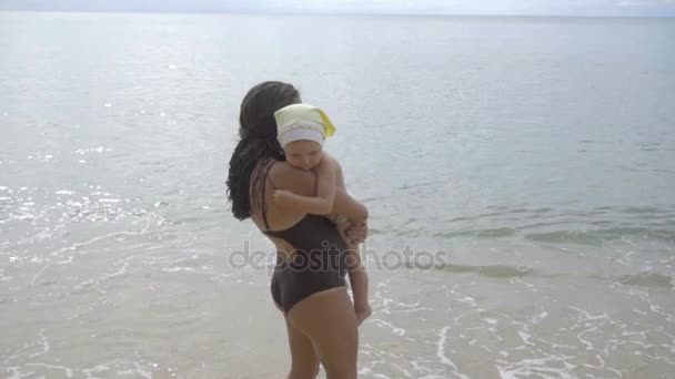 Maman avec une fille de deux ans marchant le long de la plage de sable — Video