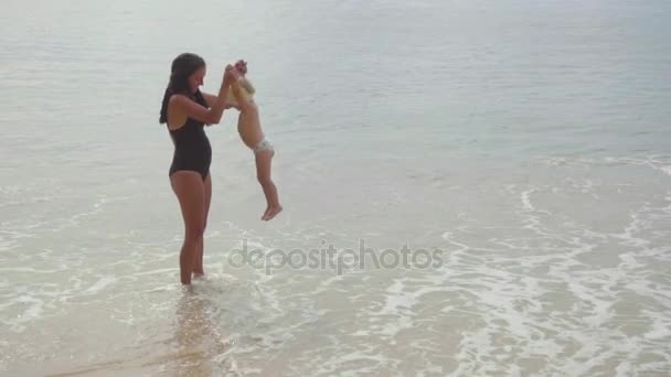 Мама с двухлетней дочерью прогуливается по песчаному пляжу — стоковое видео