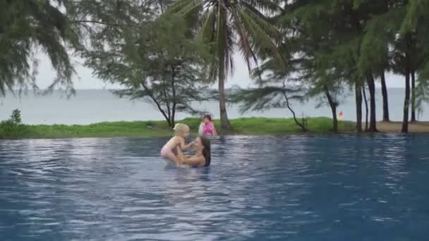 Mamá con una hija de dos años en la piscina del hotel cerca del océano — Vídeo de stock