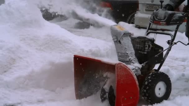 Hombre con una máquina de soplado de nieve trabajando — Vídeo de stock