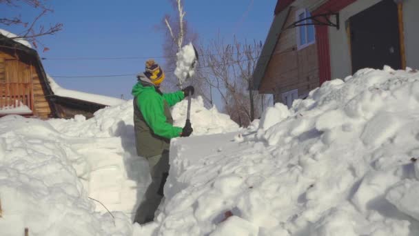 Чоловік скидає сніг після снігової бурі — стокове відео