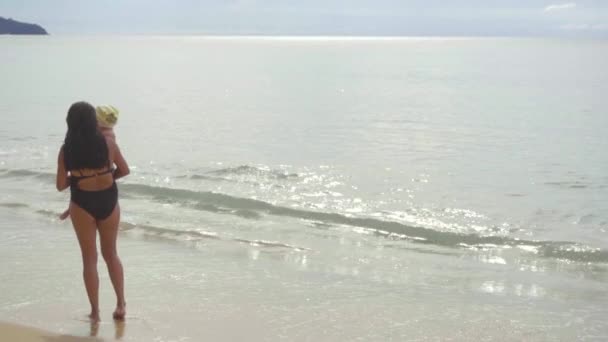 Мама с двухлетней дочерью прогуливается по песчаному пляжу — стоковое видео