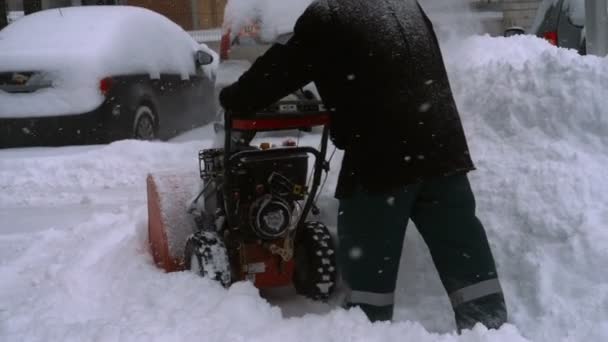 Hombre con una máquina de soplado de nieve trabajando — Vídeos de Stock