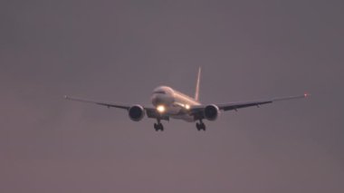 Gün batımında okyanus üzerinden yaklaşan uçak.