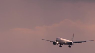 Gün batımında okyanus üzerinden yaklaşan uçak.