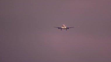 Gün batımında okyanus üzerinden yaklaşan uçak.
