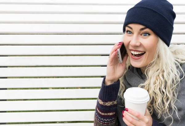 Девушка в зимней одежде разговаривает по телефону и смеется — стоковое фото