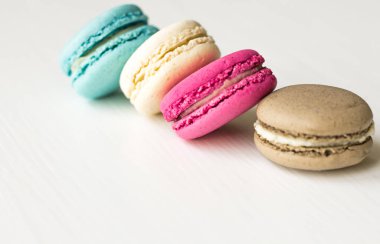 Macaron pasta, mavi, pembe, sarı, kahverengi beyaz arka plan üzerinde