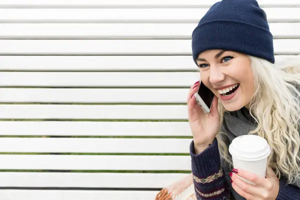 Жінка з телефоном і кавою в руці сміється — стокове фото