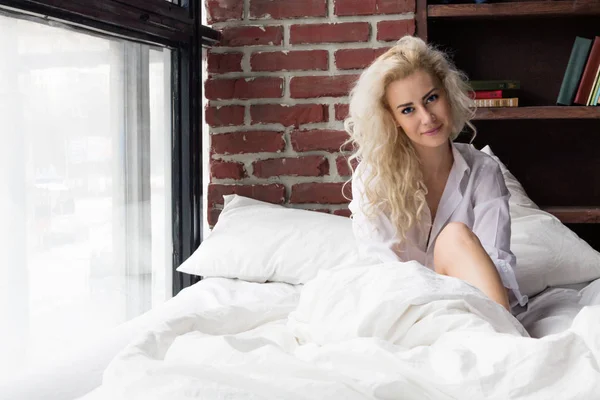 Молода жінка Прокинувшись в білий ліжко — стокове фото