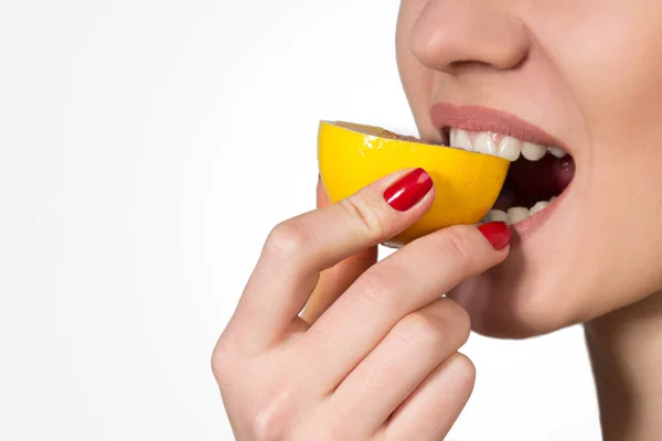 Woman with a Bright Manicure Tastes a Lemon Royalty Free Stock Photos