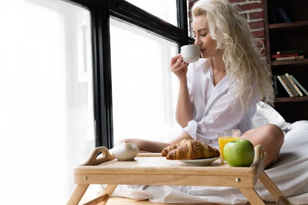 Молодая женщина наслаждается кофе в постели — стоковое фото