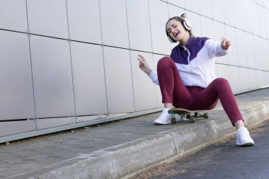 Müzik ve şarkı söyler bir kaykay üzerinde genç kız dinler