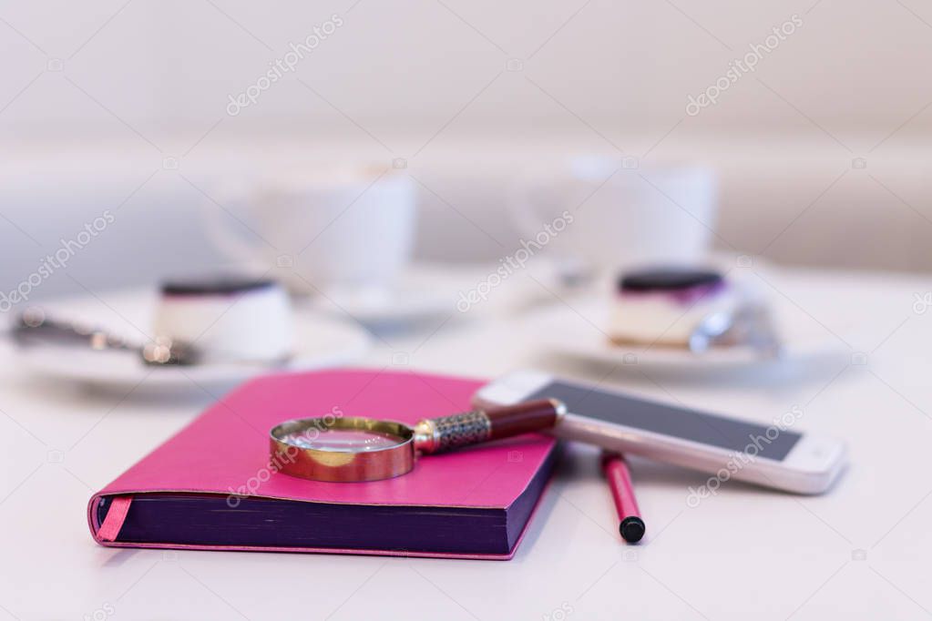 A Notebook with a Pen on the Background of a Pair of Coffee