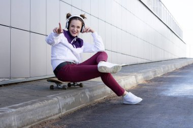 Müzik ve şarkı söyler bir kaykay üzerinde genç kız dinler