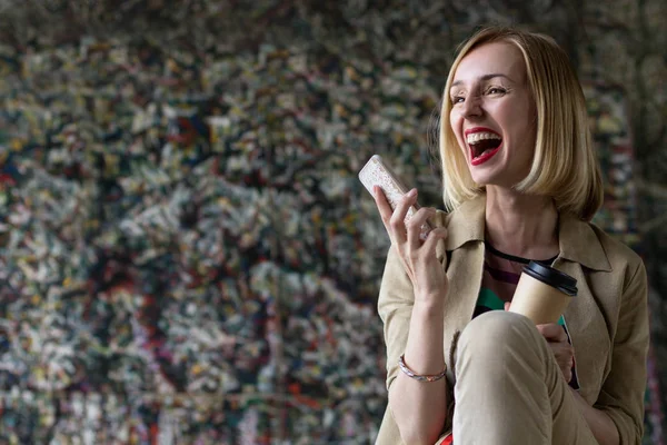 Жінка щаслива з телефоном і кавою в руках — стокове фото