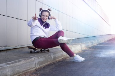 Müzik ve şarkı söyler bir kaykay üzerinde genç kız dinler