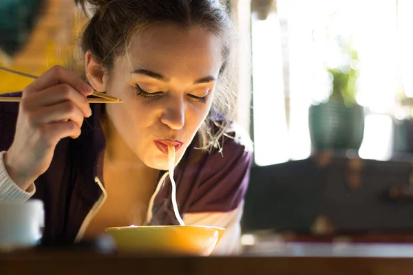 Молодая женщина ест с палочками — стоковое фото