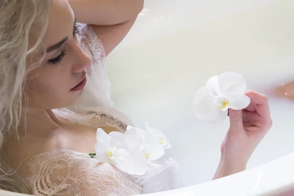 Atractiva mujer en el baño con flores y leche — Foto de Stock