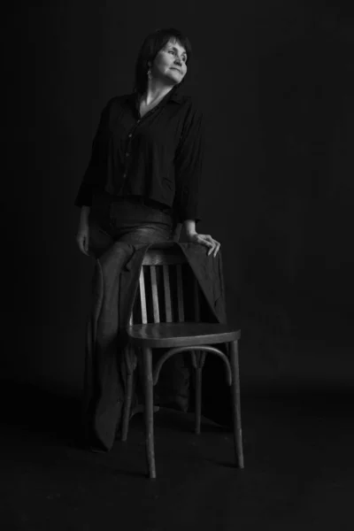 Pensive Woman Bruneta středního věku s pánskou bundou v tmavém interiéru — Stock fotografie
