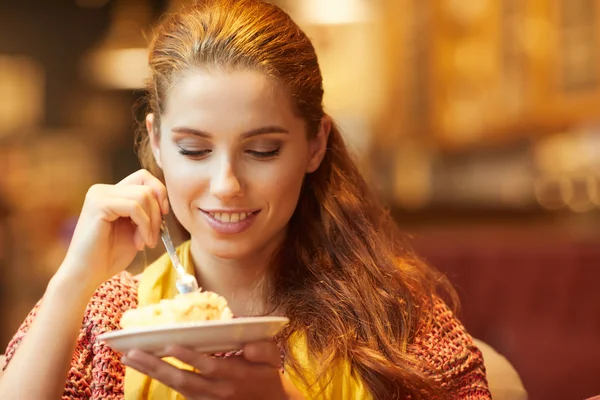 Young beautiful woman in a cafe eating cake — Stock Photo, Image