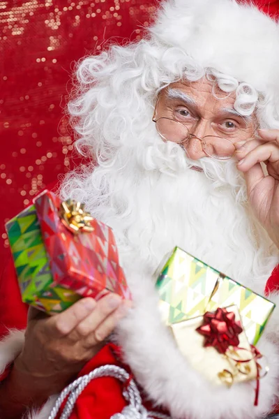 Santa claus biedt een rode geschenk tegen rode achtergrond — Stockfoto