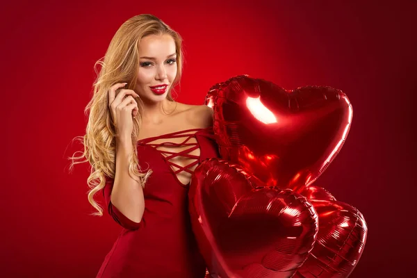 Hermosa mujer rubia posando con globos del corazón — Foto de Stock